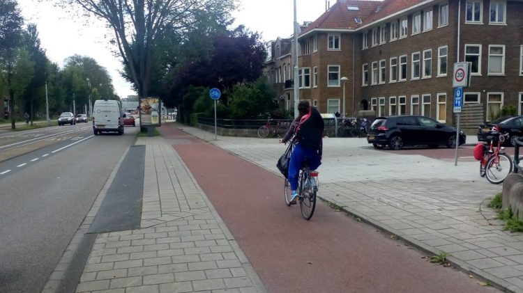 Level bike path and sidewalk crossing a side-street/driveway where cars must change elevation to cross instead of the path/sidewalk coming down to street level.
